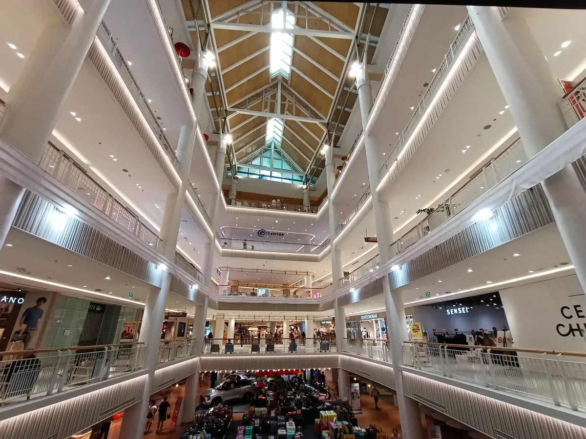 Bright multi-storey atrium with a glass roof, white balconies and escalators.
