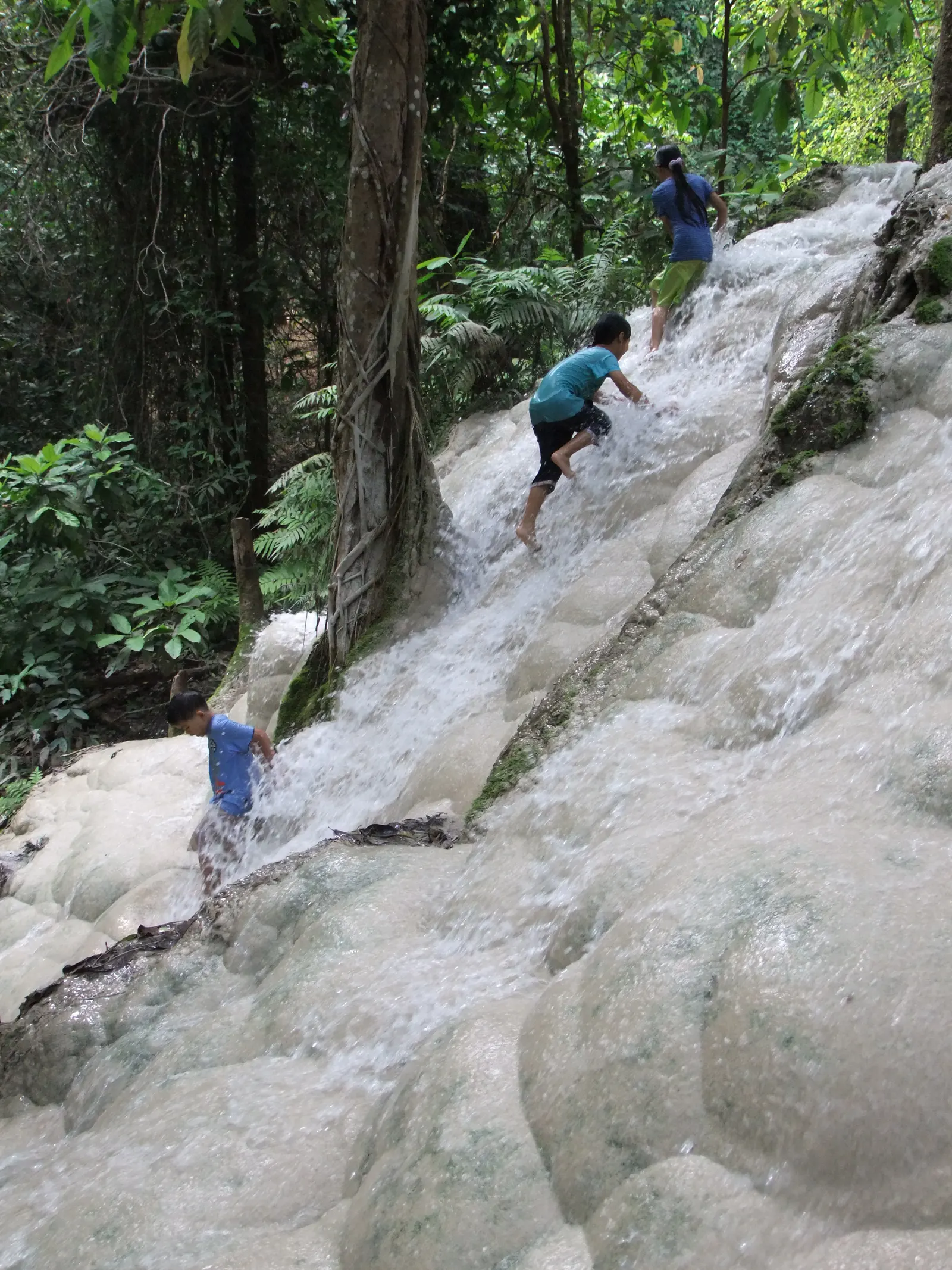 Climbers on a wide sloping sheet of white rock with water running over it