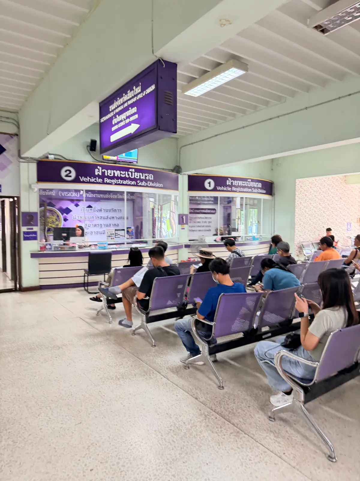 Waiting chairs in front of the vehicle registration counters with purple signs.