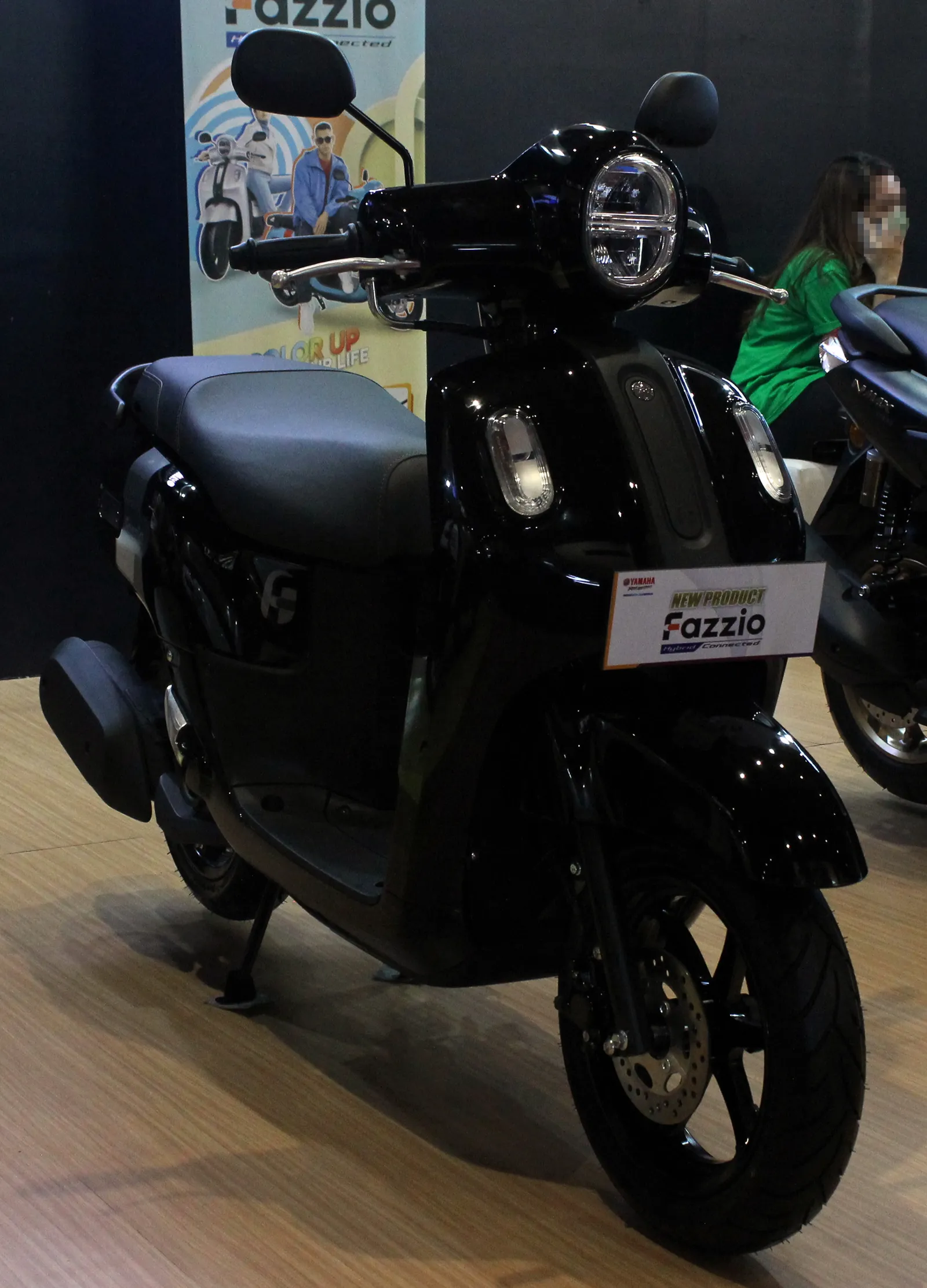 Black Yamaha Fazzio scooter on a showroom floor with a Fazzio sign on the front.