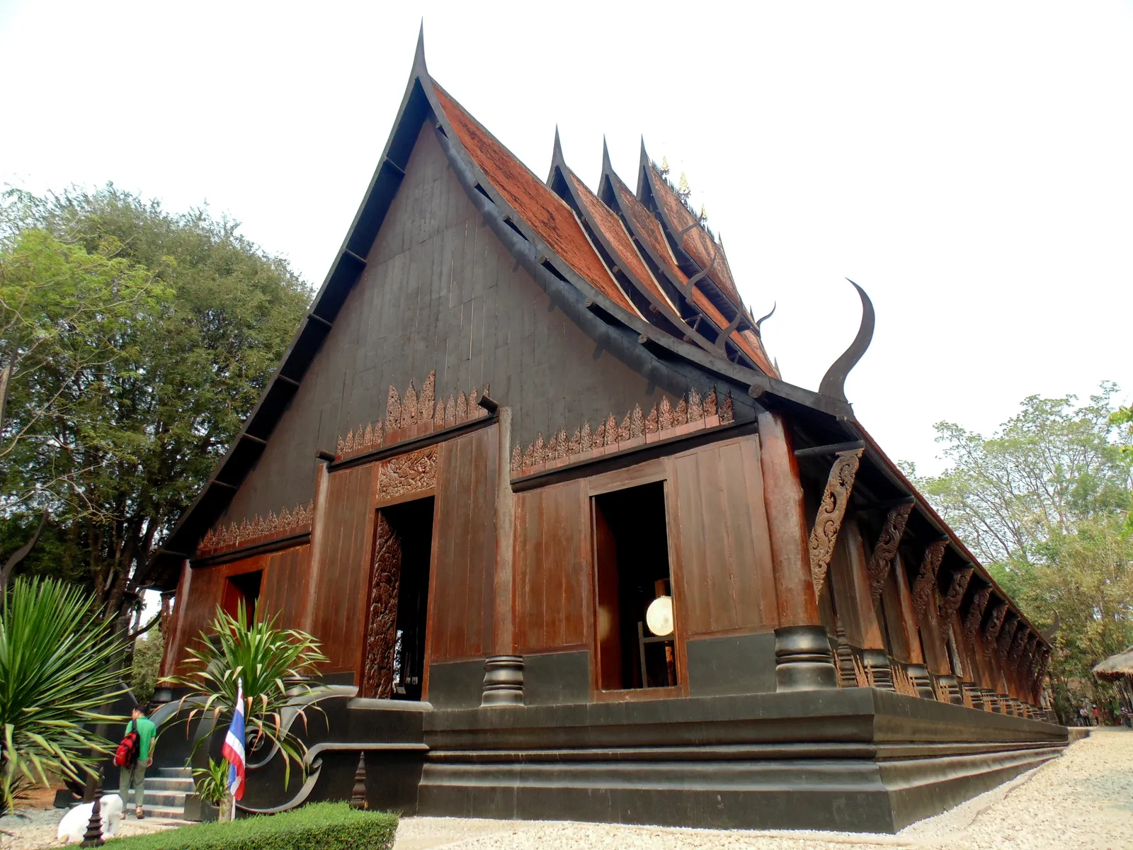 Large dark wooden house with a steep tiered roof and curved horns on the ridge