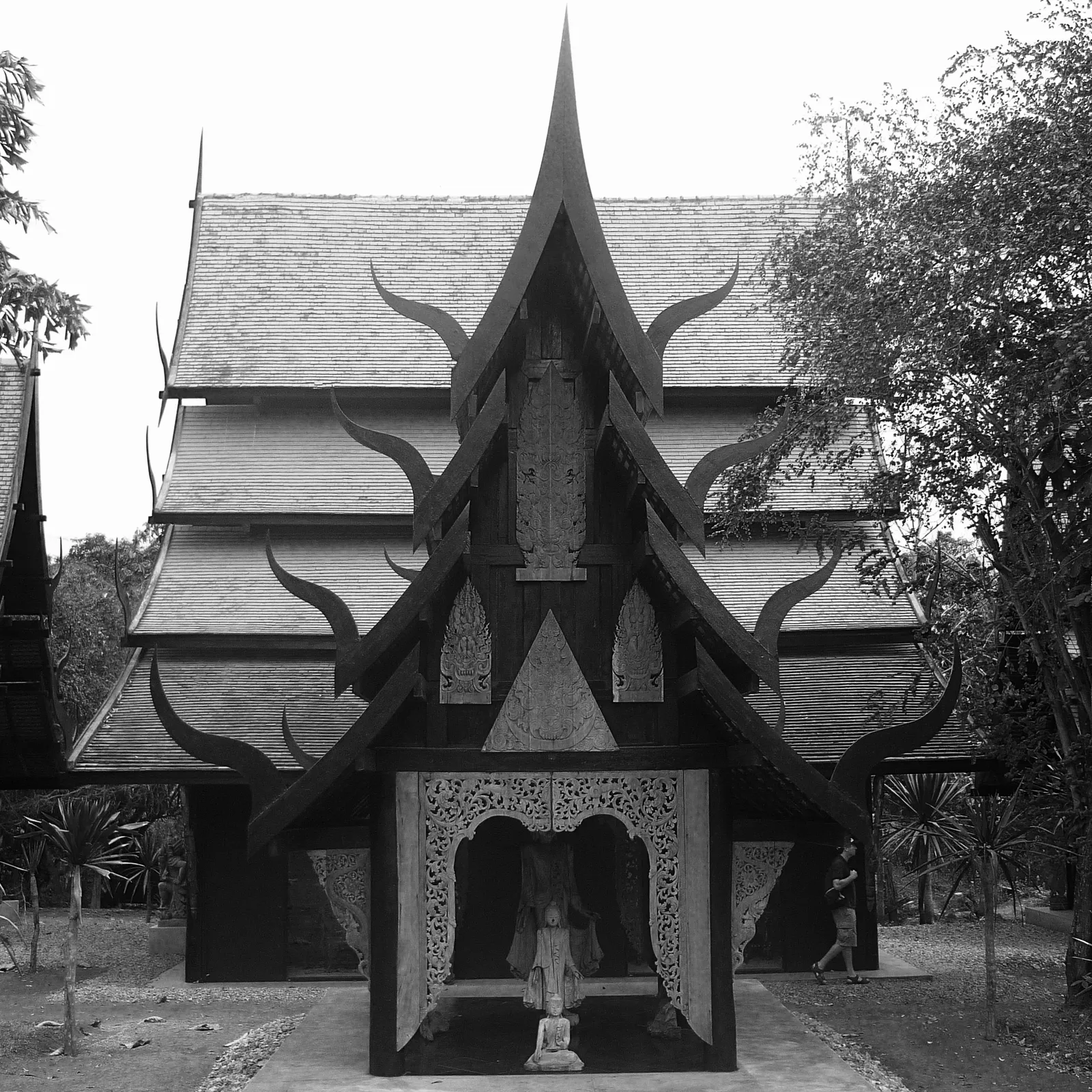 Black and white photo of a tall dark wooden house with spiked gables