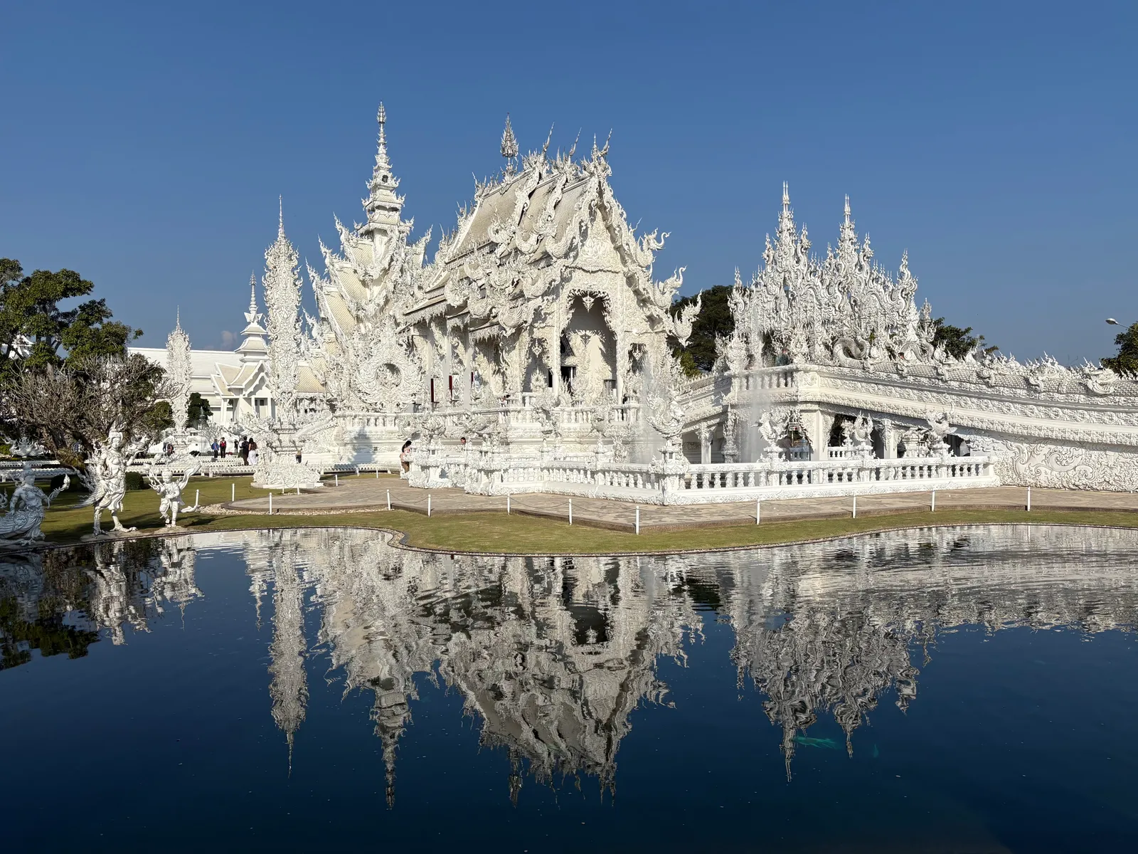White temple reflected in a still pond under a blue sky