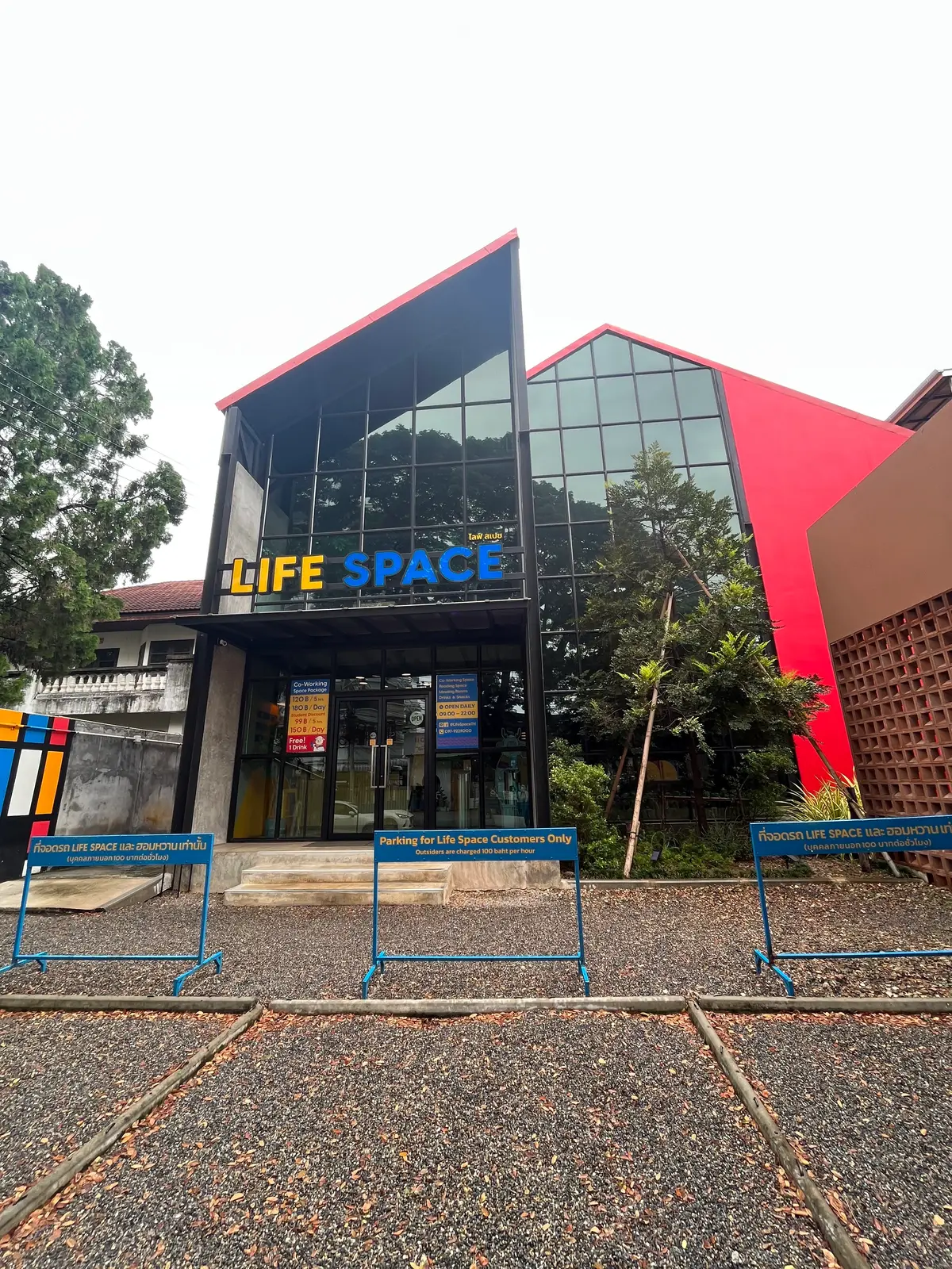 Glass-fronted building with a red side wall and a sign reading Life Space above the door.