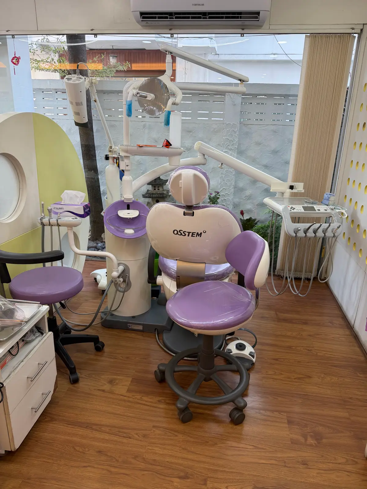 Purple dental chair and overhead light in a treatment room with a wooden floor