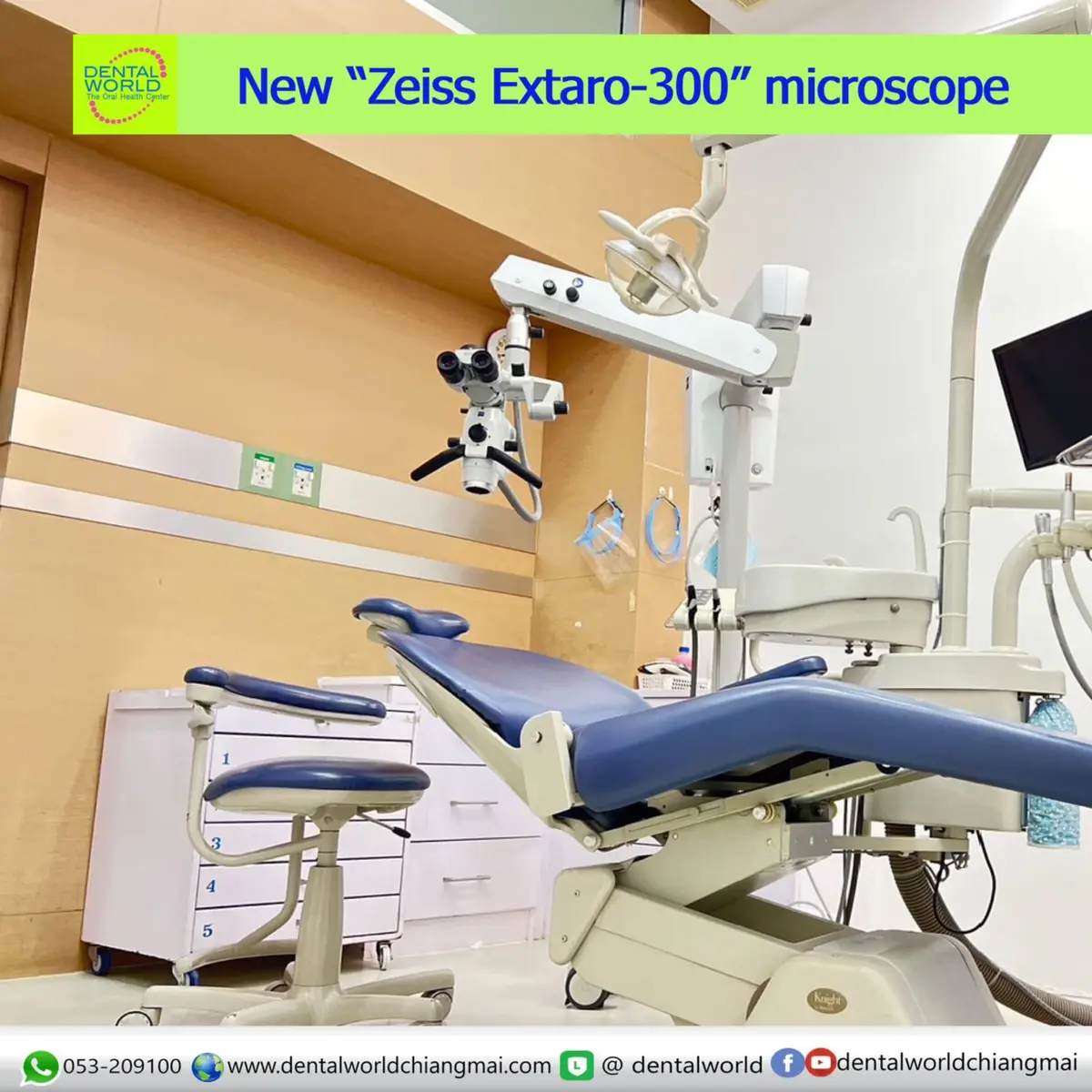 A dental treatment room with a blue reclining chair and an overhead microscope.