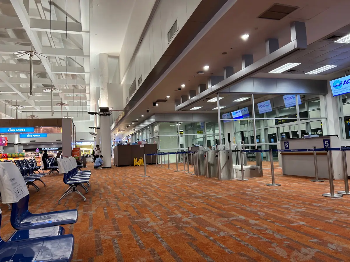 Terminal concourse with rows of seats and a service counter under a high ceiling.