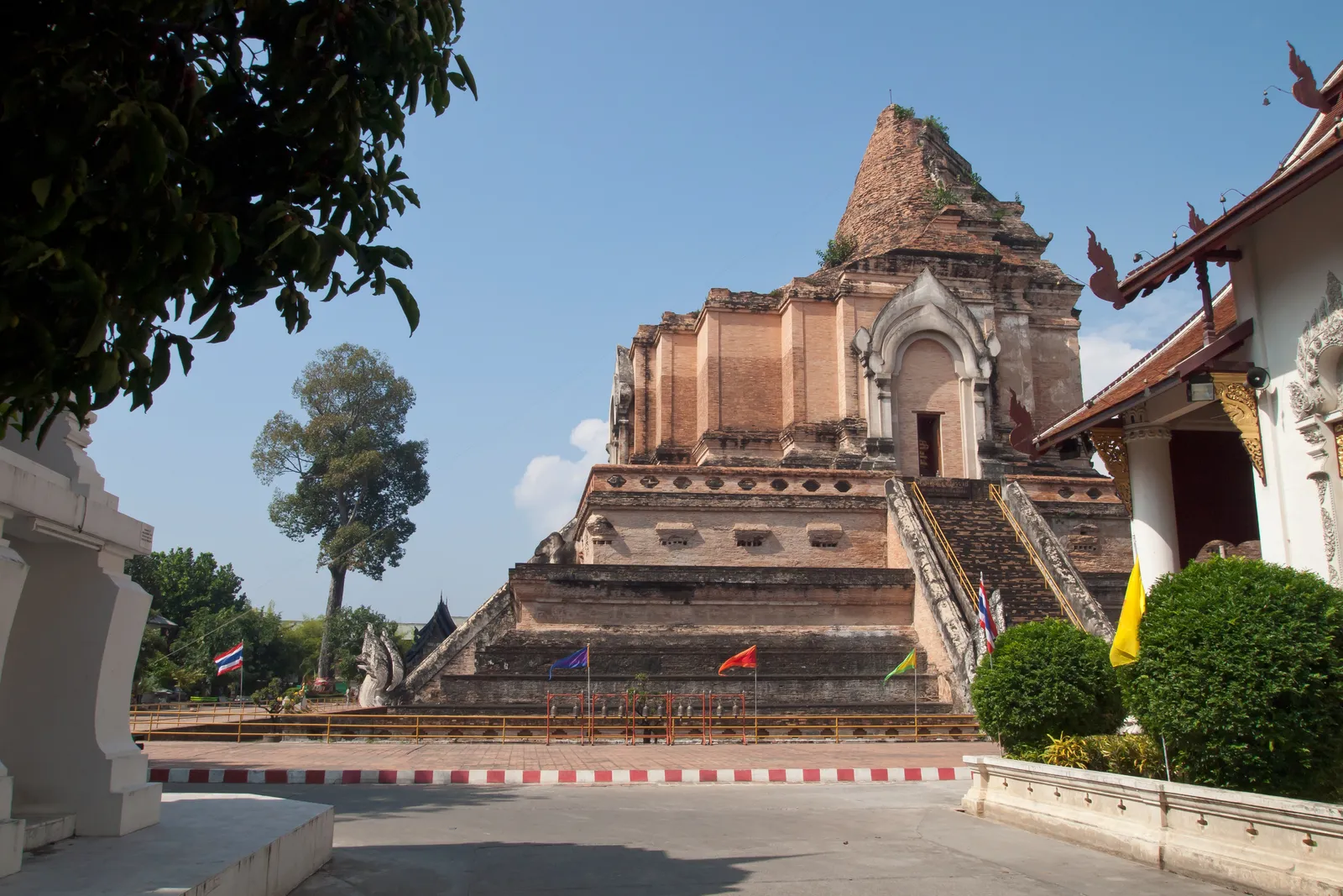 Ruined brick stupa of Wat Chedi Luang under a blue sky with trees around it.