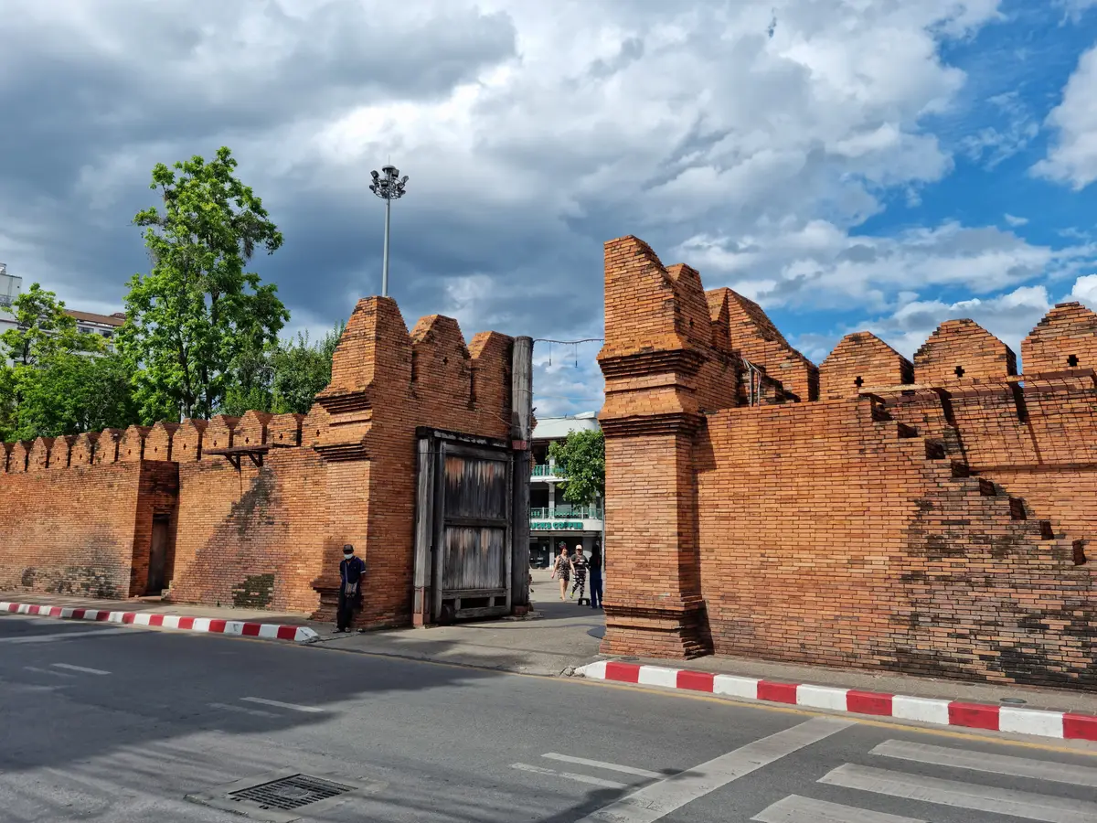 Two brick gate towers with battlements, a wide road and a red-and-white kerb
