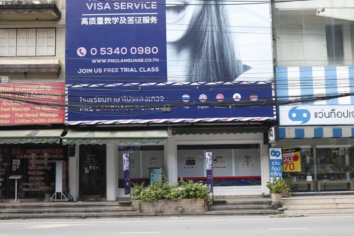 Street front of a shophouse with a blue Pro Language banner, a phone number and a free trial class notice