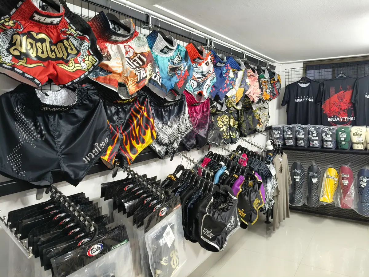 Wall of colourful Muay Thai shorts and boxing gloves on shelves in a shop.