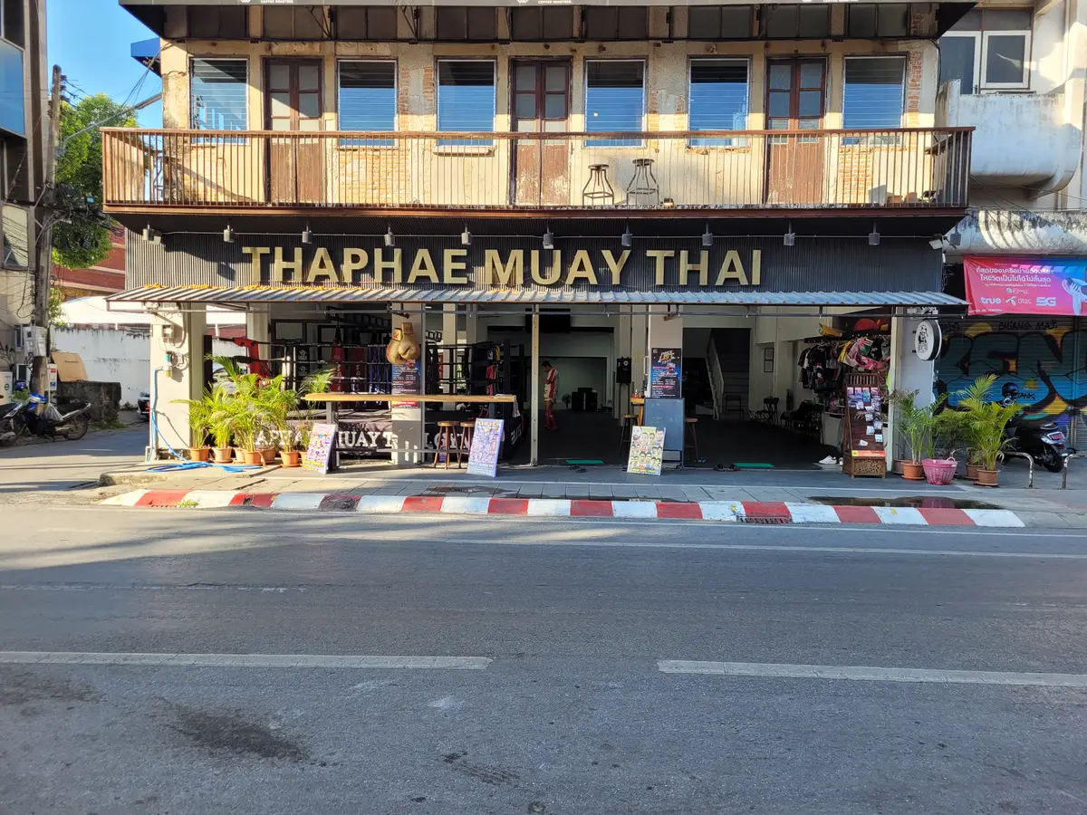 Shopfront on a street with a sign reading Thaphae Muay Thai over an open doorway.