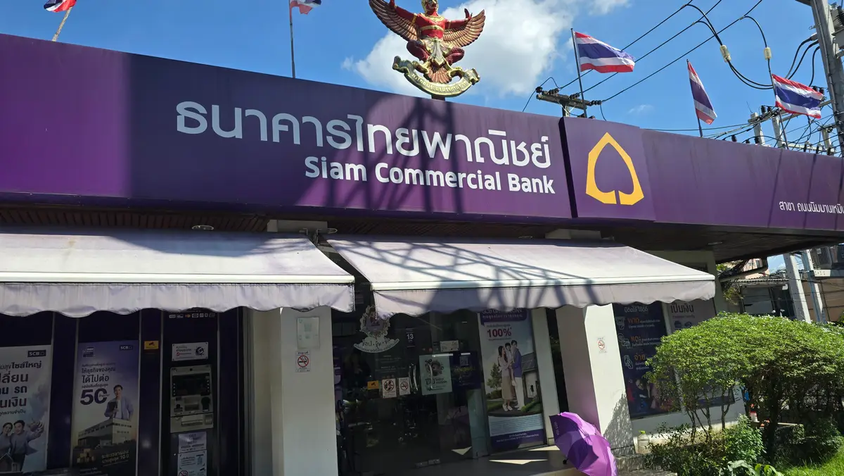 Purple Siam Commercial Bank sign with Thai lettering above the branch entrance and a Thai flag on the left.