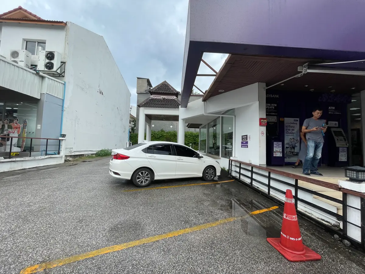 Single-storey SCB branch with a white car parked in front and an orange traffic cone on the ground.