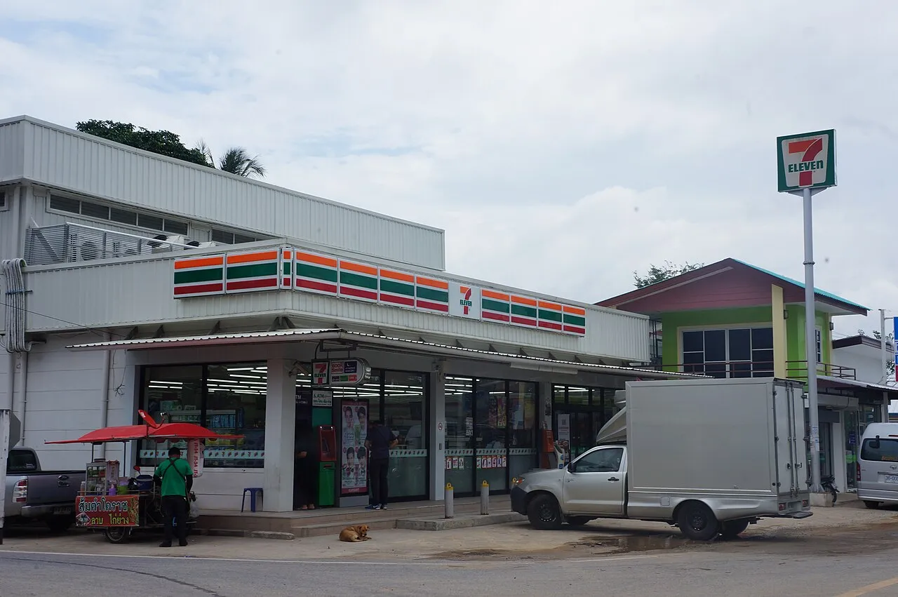 7-Eleven convenience store with a striped awning and a pickup truck parked outside.