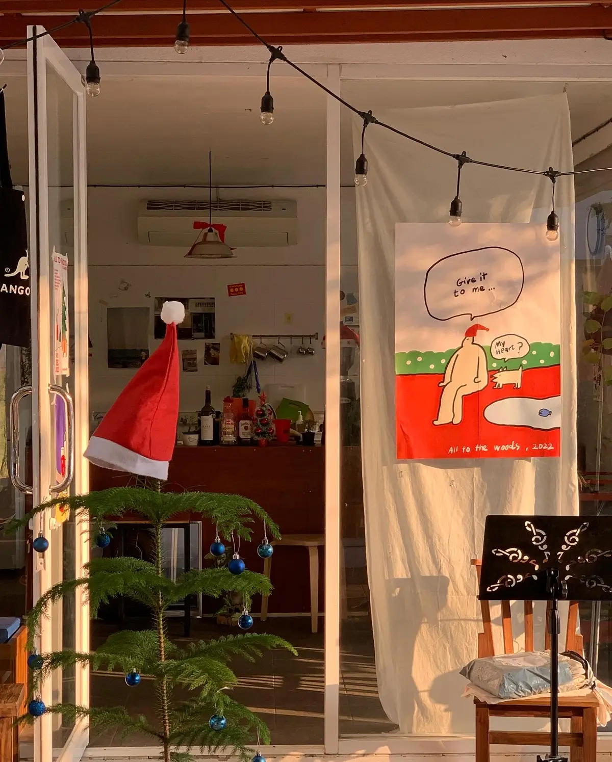 Cafe doorway hung with a red Santa hat, a poster and string lights