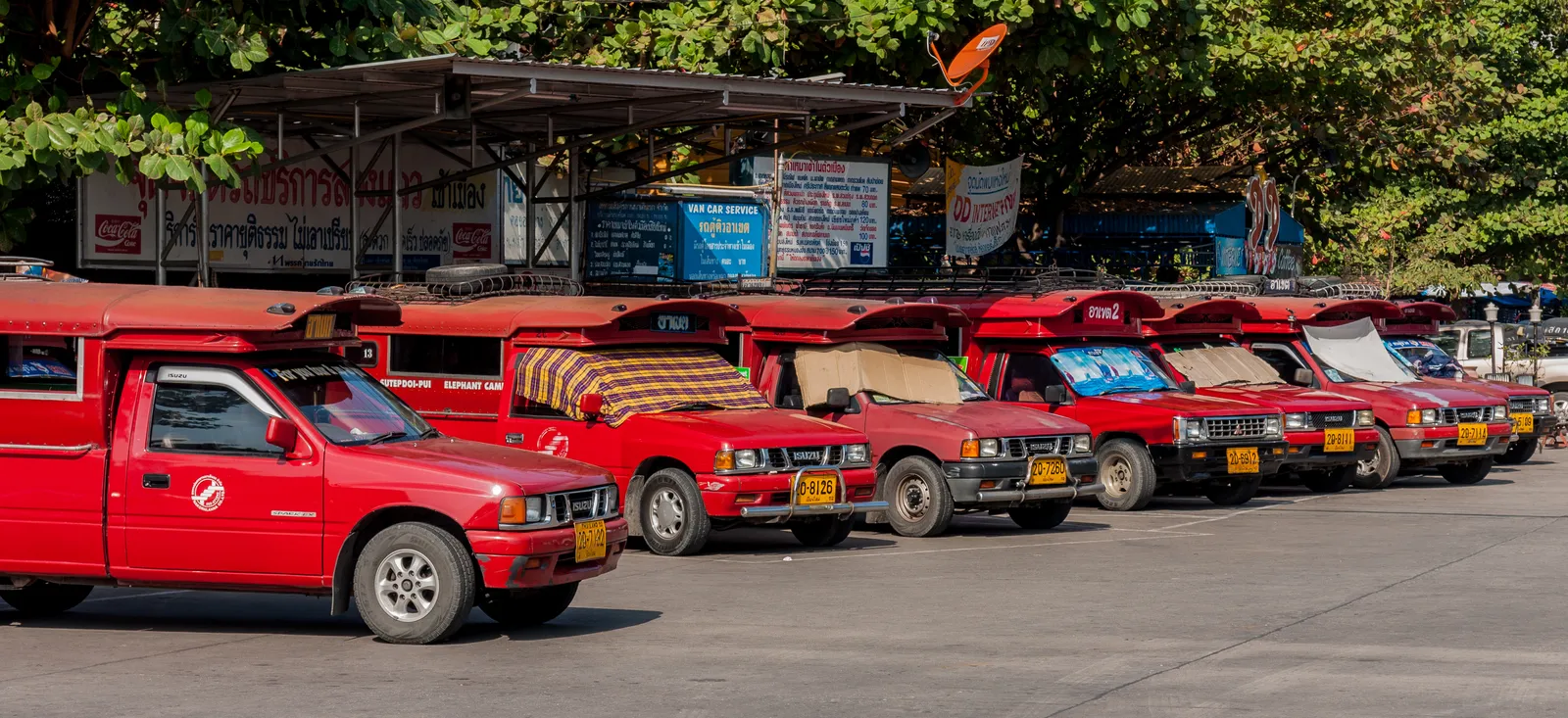 Row of red pickup trucks parked under a roof at a bus station