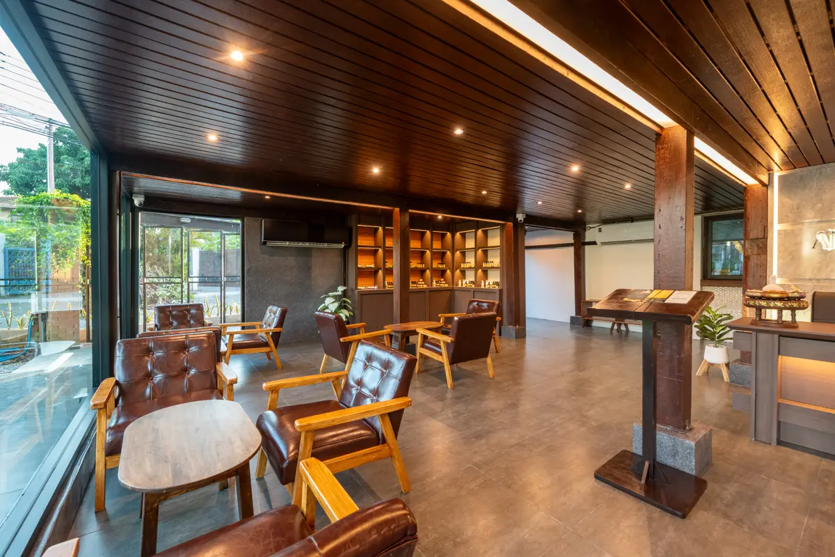 A bright lounge with leather chairs, a wooden ceiling and bookshelves beyond glass walls.