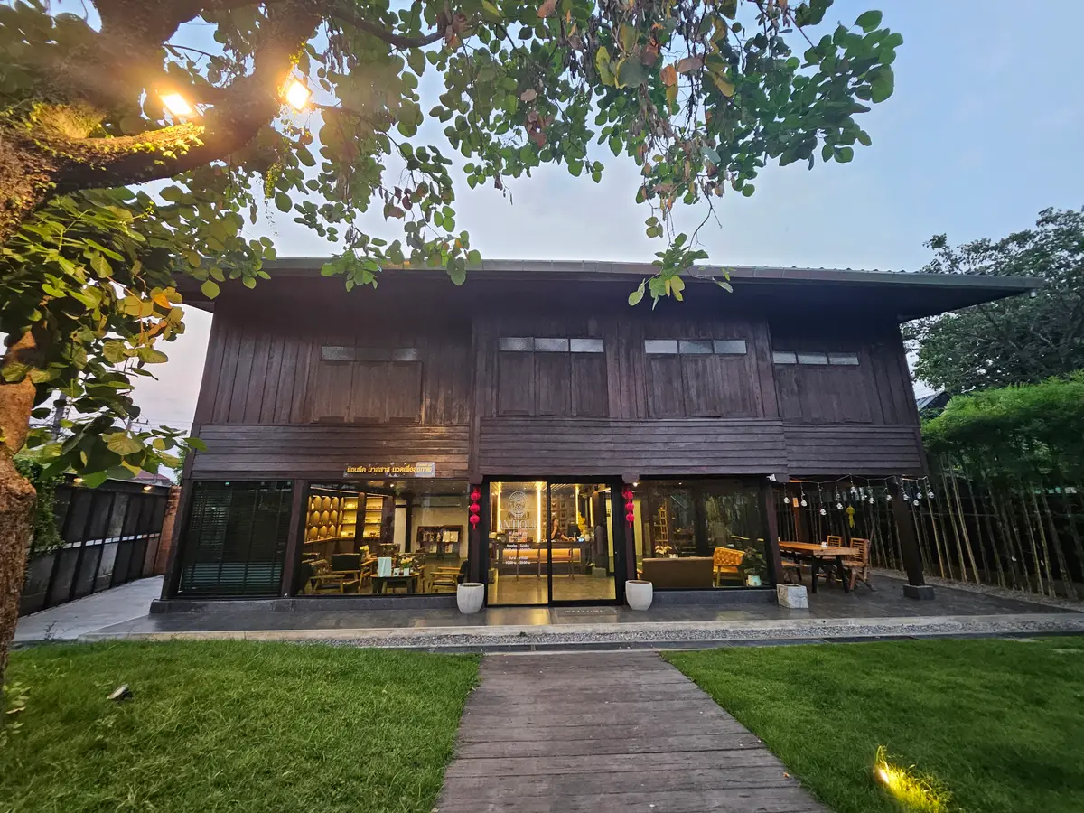 A traditional wooden house raised on posts, with a lawn and a stone path leading to it.