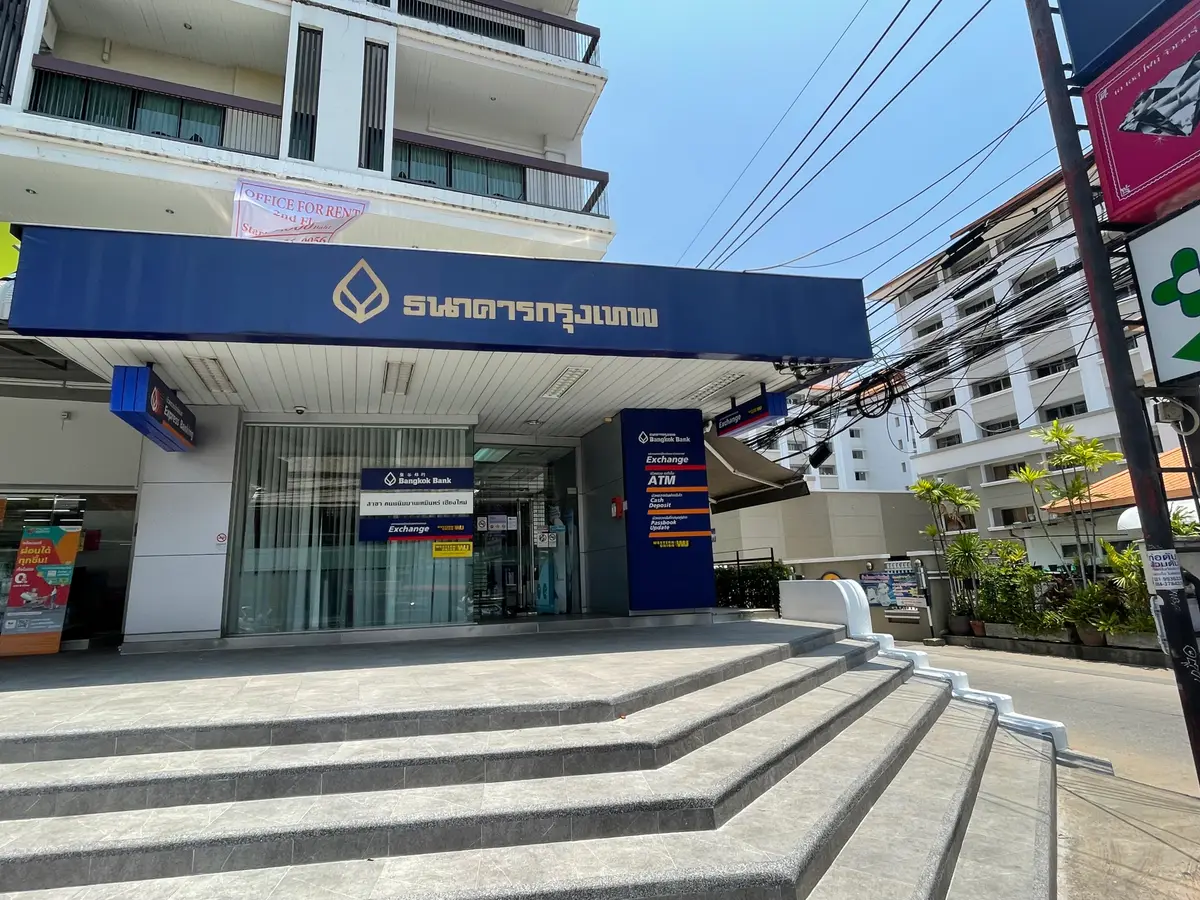 Bangkok Bank branch entrance with a blue sign over glass doors above wide stone steps.