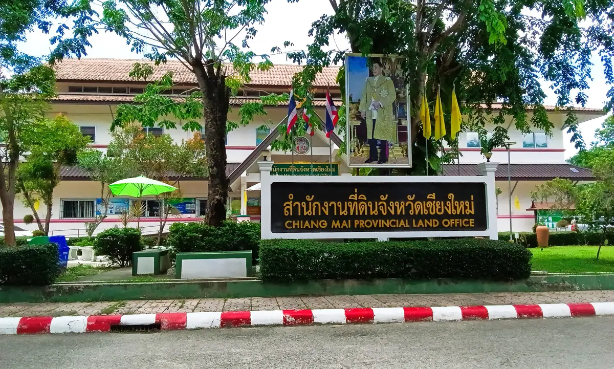 Entrance sign reading Chiang Mai Provincial Land Office in front of a low building with flags.