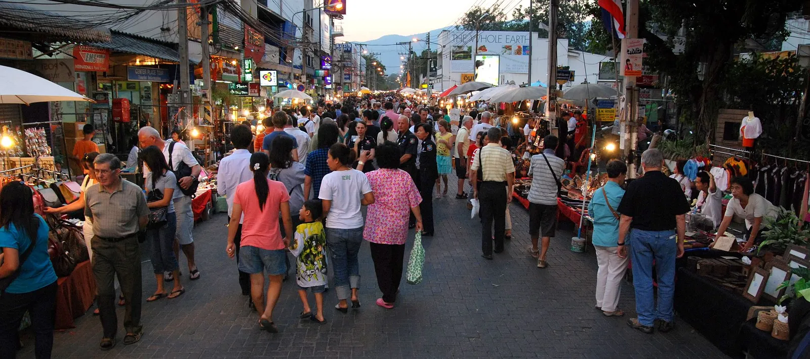 Wide street full of walkers between lines of market stalls on a Sunday evening.
