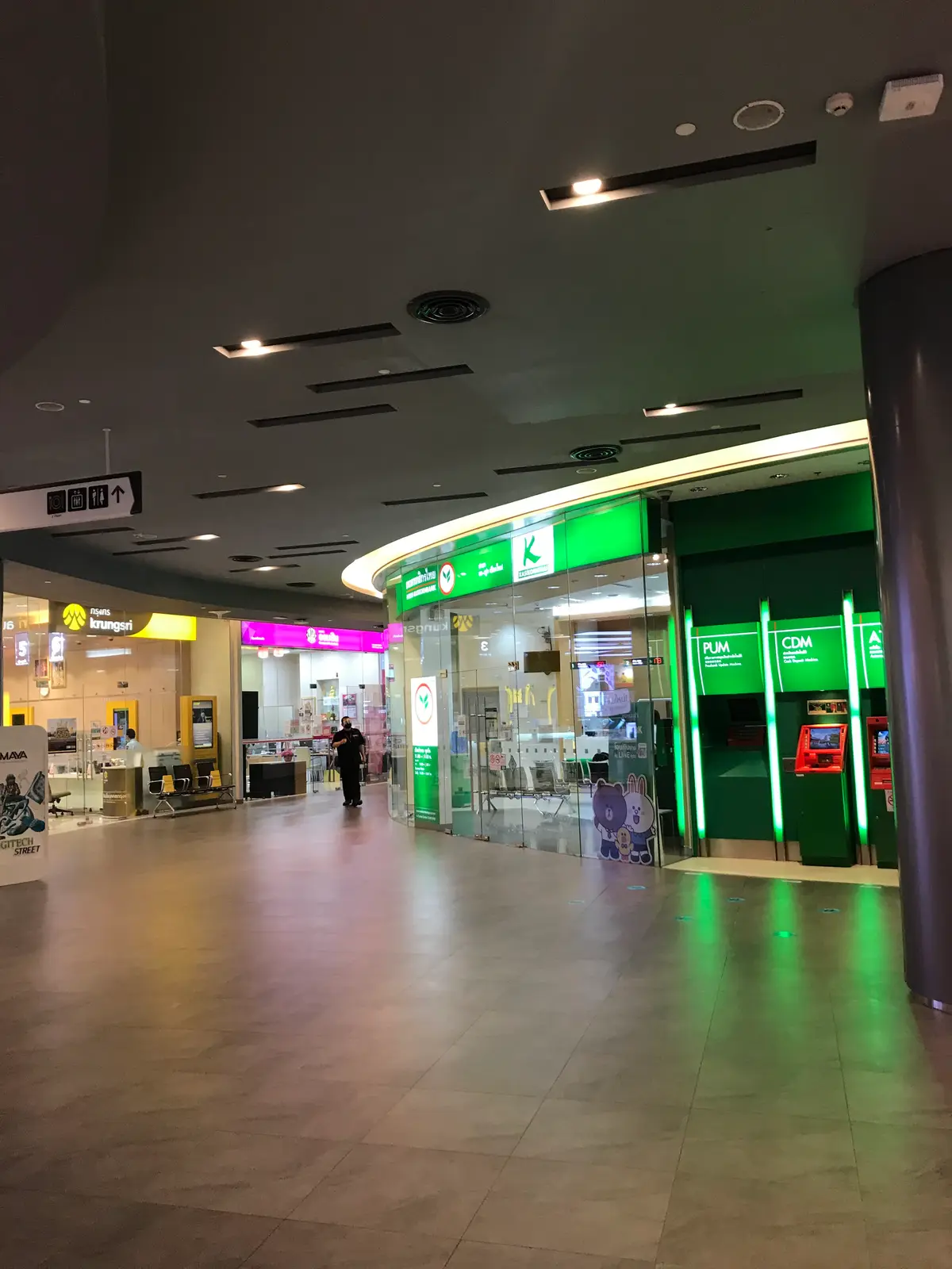 Green-lit Kasikornbank ATM bay at the end of a shopping mall corridor.
