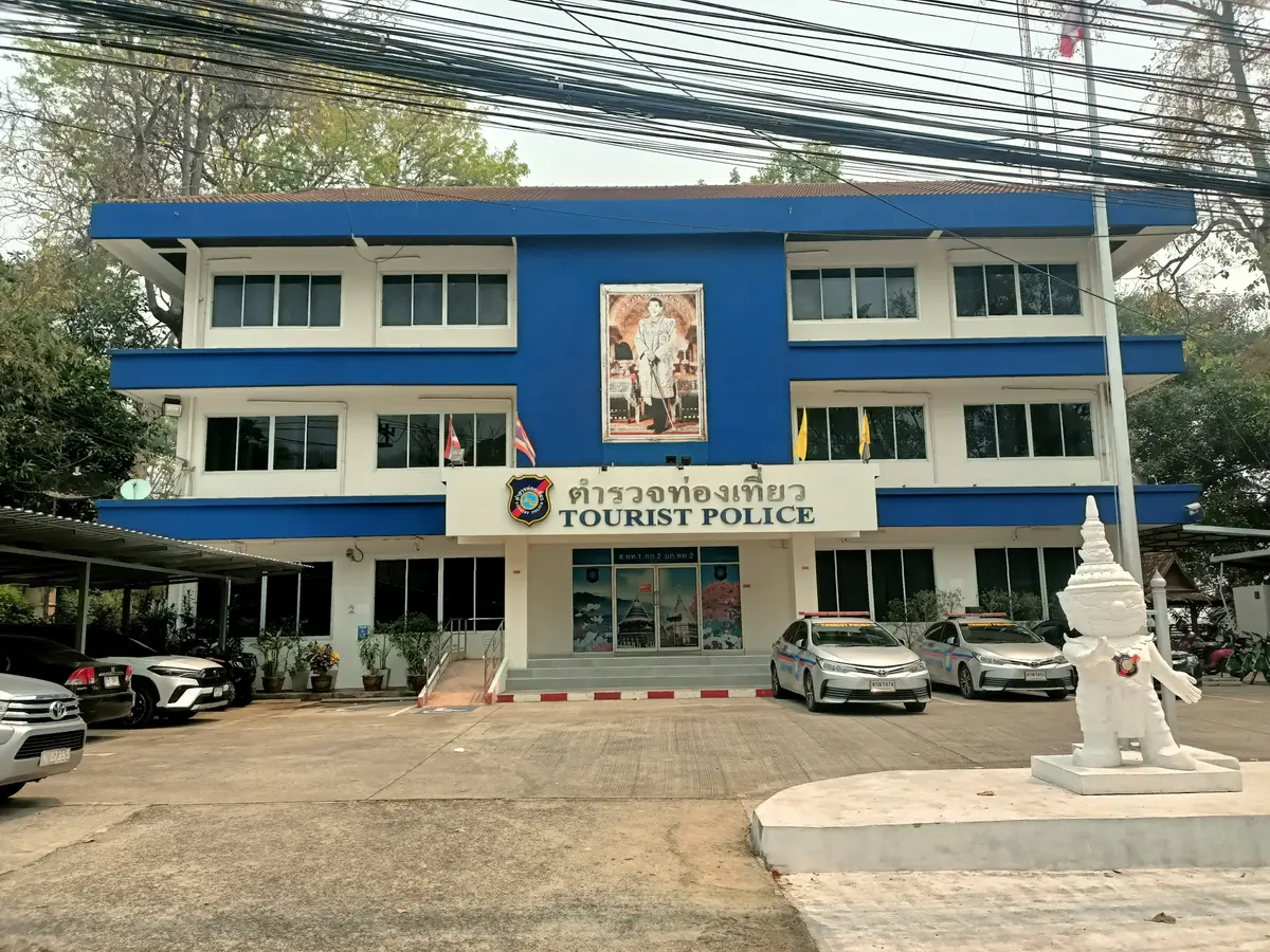 Blue and white two-storey police building with a Tourist Police sign and parked cars.
