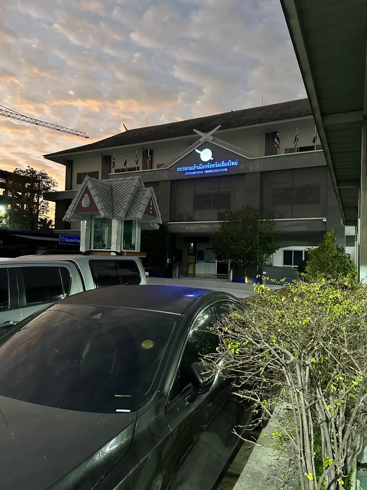 Front of the Chiang Mai Immigration office building at dusk, with a Thai sign above the entrance.